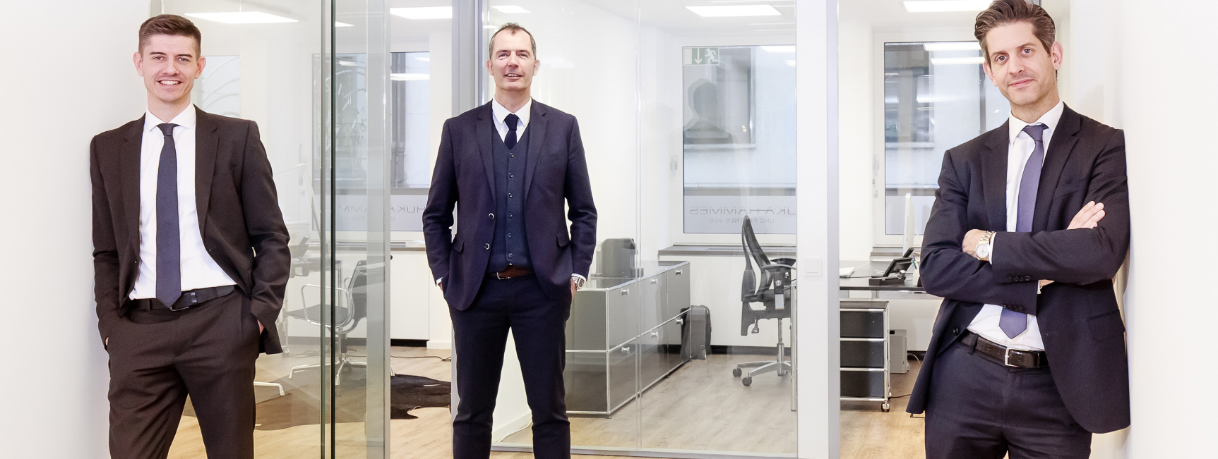 Foto auf dem die Partner der Kanzlei stehend fotografiert sind.